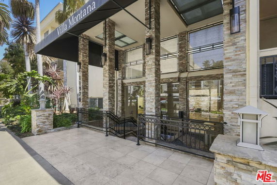 Front view of a building entrance with a stone facade and glass windows.