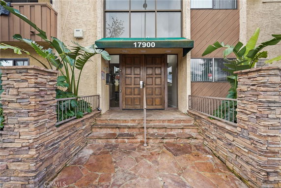 Front view of a building entrance with stone walls and a wooden door.