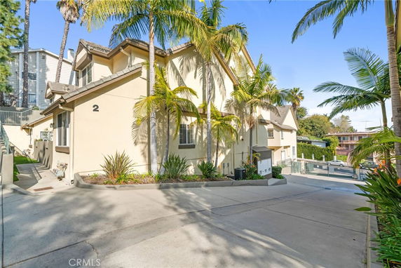 Front view of a multi-story house with gable roof and palm trees.