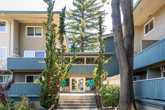 Front view of a multi-story residential building with multiple windows and a staircase leading to the entrance.