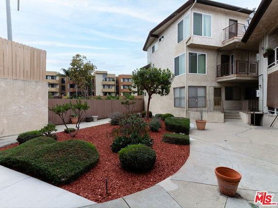 Exterior view of a multi-story residential building with balconies and surrounding landscaping.