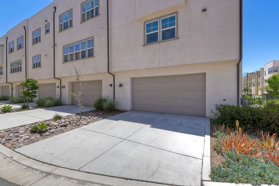 Front view of a multi-story building with garage and driveway.