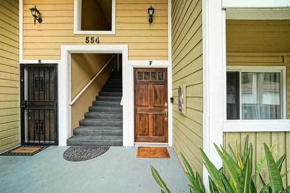 Front view of a multi-story building entrance with stairs and wooden door.