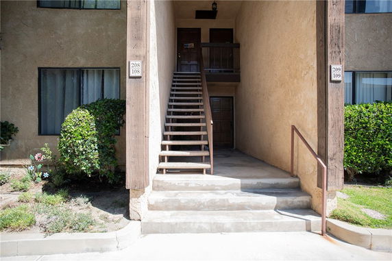 Front entrance view of a two-story apartment building with an exterior staircase.