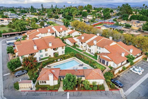 Aerial view of a residential complex with red-tiled roofs and a central swimming pool.