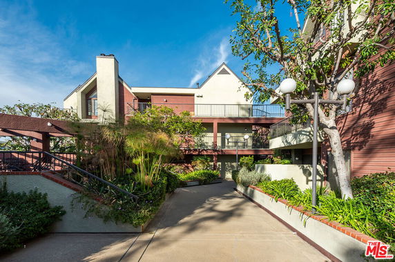Front view of a multi-story building with balconies and a landscaped pathway.