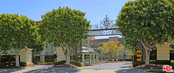 Front view of a gated entrance with ornate ironwork and surrounding trees.