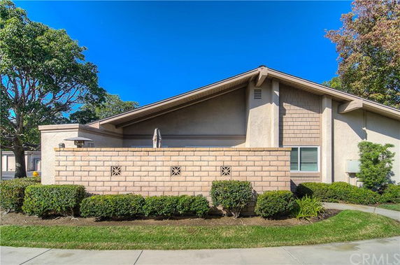 Front view of a single-story house with a sloped roof and brick wall.