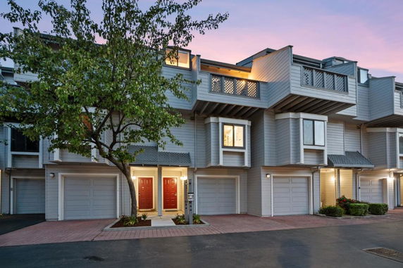 Front view of a multi-story townhouse with garages and red front doors.