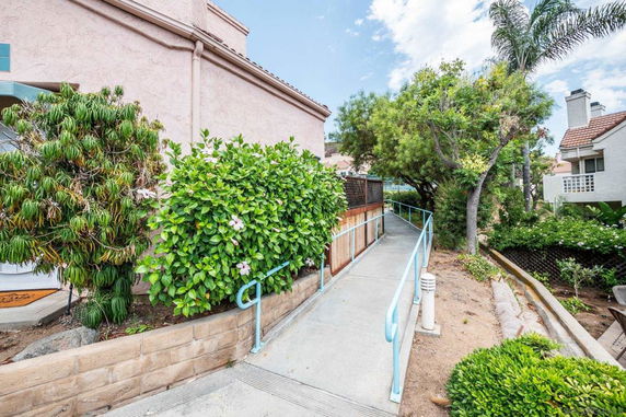 Side view of a building with a walkway surrounded by greenery.