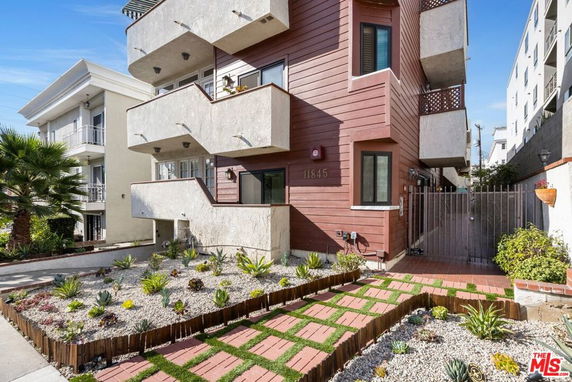 Front view of a multi-story building with balconies and a landscaped garden.