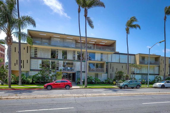Front view of a multi-story modern building with large windows and balconies.