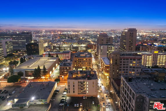 Panoramic view of a cityscape at dusk with illuminated buildings and streets.
