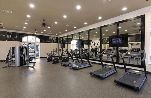 Indoor fitness gym with exercise equipment and mirrors.