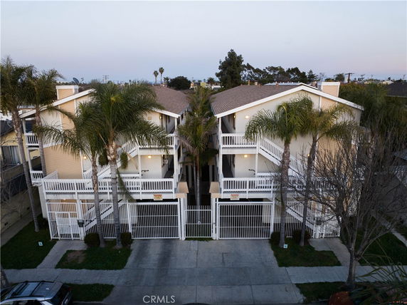 Front view of a two-story residential building with multiple balconies and a gated entrance.
