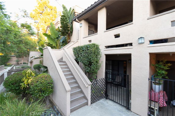 Two-story residential building with stairs leading to the second floor and a small patio area on the ground floor.