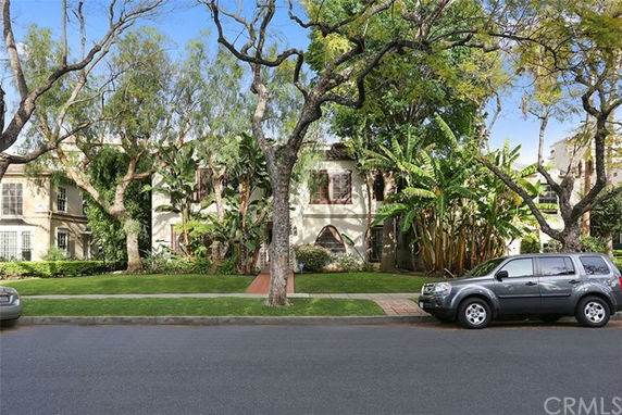 Front view of a two-story house with trees and parked cars.
