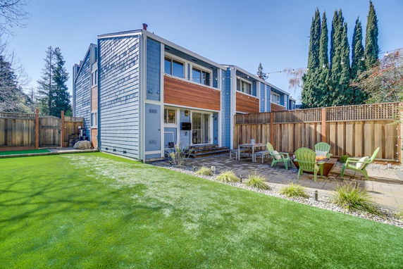 Rear view of a modern two-story house with a patio and seating area.
