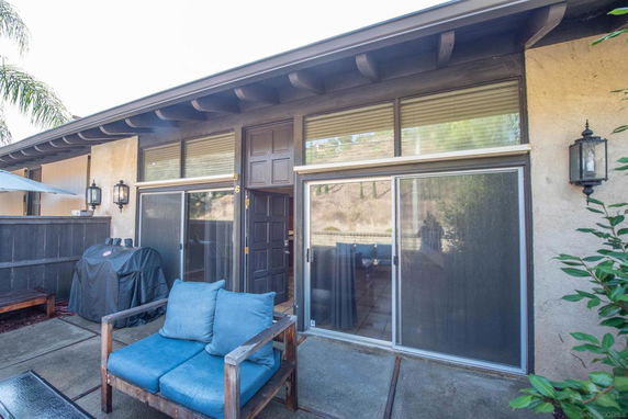 Front view of a house with sliding glass doors and outdoor seating area.