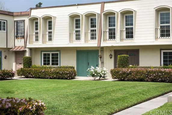 Front view of a two-story townhouse with arched windows and a landscaped front yard.