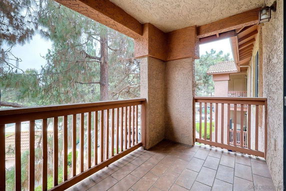 View from the balcony showing nearby trees and part of the building exterior.
