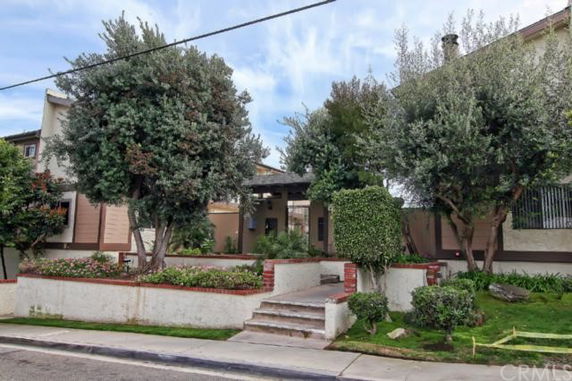 Front view of a house with trees and landscaped garden.