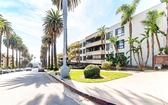 Front view of a multi-story apartment building with balconies and large windows.