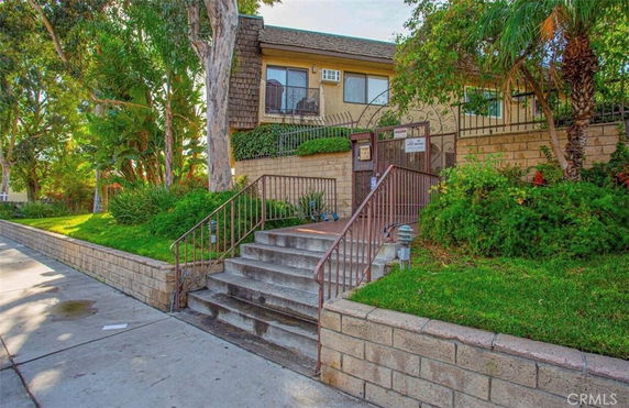 Front view of a house with steps leading to the entrance and lush greenery surrounding the exterior.