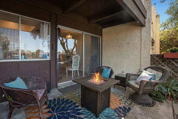 Outdoor patio area with wicker chairs and a fire pit table.