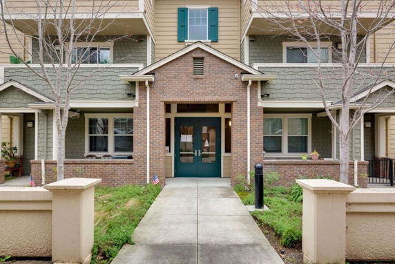 Front view of a multi-story building with green shutters and brick entrance.