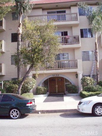 Front view of a multi-story residential building with balconies and an entrance.