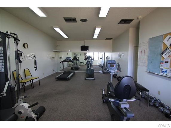 Indoor gym area with exercise equipment and mirrors on the walls.