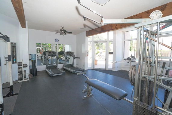 Interior view of a gym with exercise equipment including treadmills, weight machines, and dumbbells.