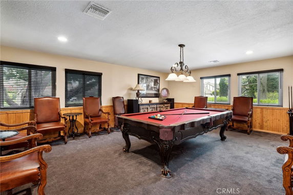 Room with a pool table and several leather chairs.