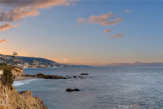 Panoramic view of a coastal area with cliffs and ocean at sunset.