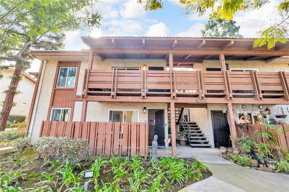 Front view of a two-story building with wooden balconies and a stairway entrance.