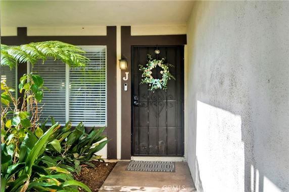 Front view of a house with a decorative wreath on the front door and adjacent windows.