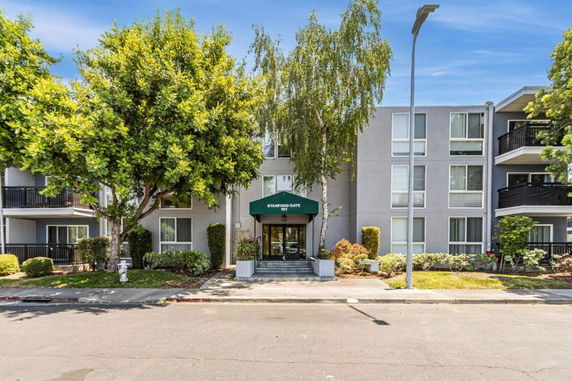 Front view of a three-story apartment building with a central entrance covered by a green awning.
