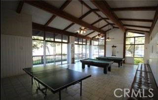 Room with billiards and table tennis tables, large windows, and exposed ceiling beams.