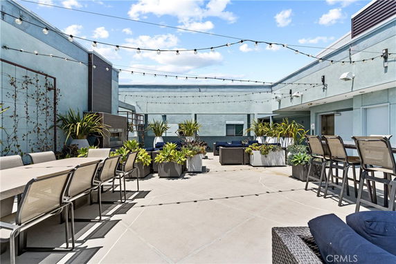 Rooftop with seating area, tables, and string lights.