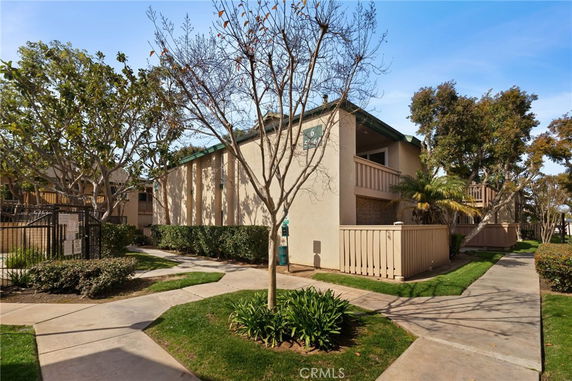 Front view of a two-story residential building with balconies and surrounding pathways.