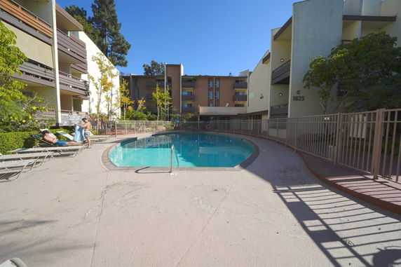 Outdoor swimming pool area surrounded by multi-story apartment buildings.