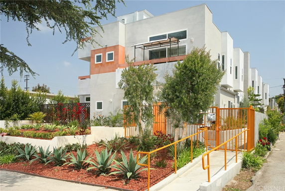 Front view of a contemporary multi-story building with a garden and pathway.