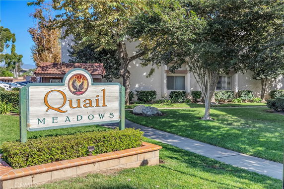Front view of a building with a sign reading 'Quail Meadows'.