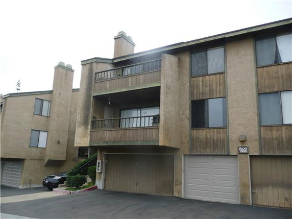 Front view of a multi-story apartment building with balconies and garages.