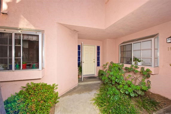 Front view of a house entrance with a white door and two windows.