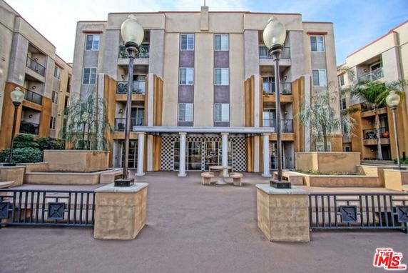 Front view of a multi-story apartment building with a central entrance and balconies.