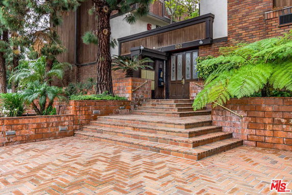 Front view of a brick building entrance with steps and planters.