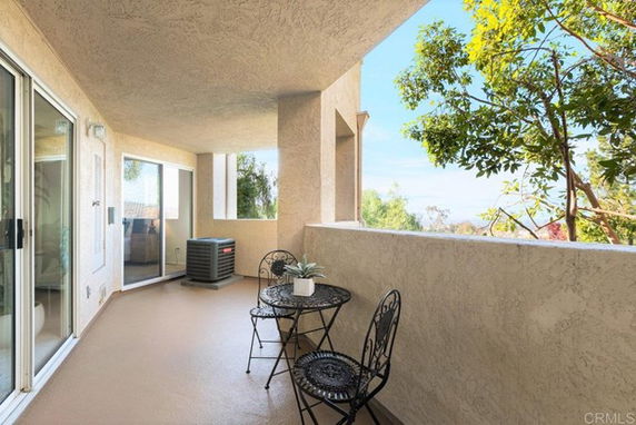 Outdoor patio area with a small table and chairs, featuring views of surrounding trees and landscape.