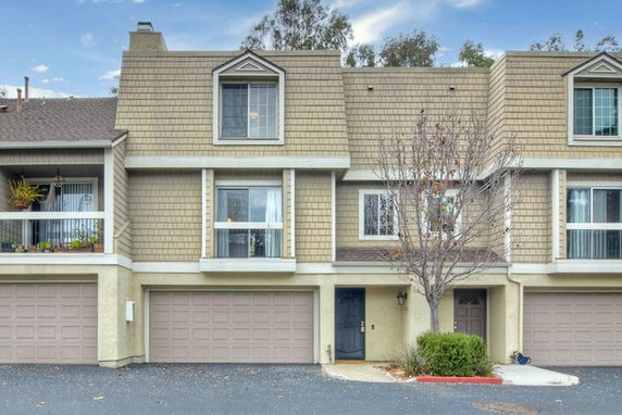 Front view of a multi-story townhouse with garages on the ground level.
